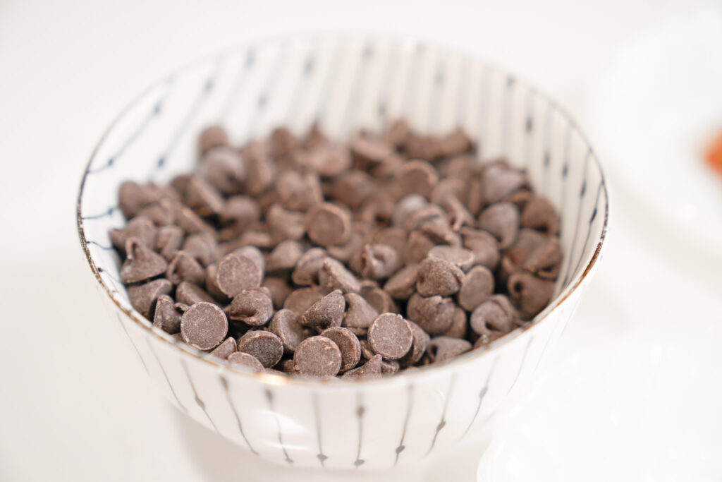 A white and black striped bowl filled with chocolate chips.