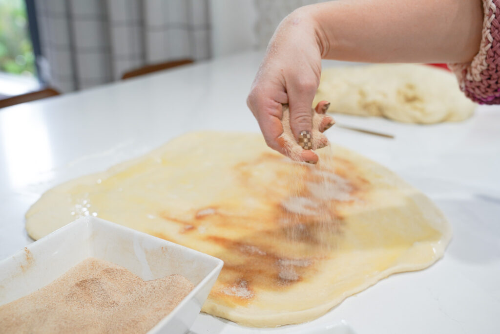 sprinkling the sugar and cinnamon over the dough