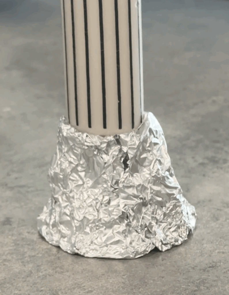 Taper candle inserted into a crumpled foil mound to form the base for a ghost candlestick holder.