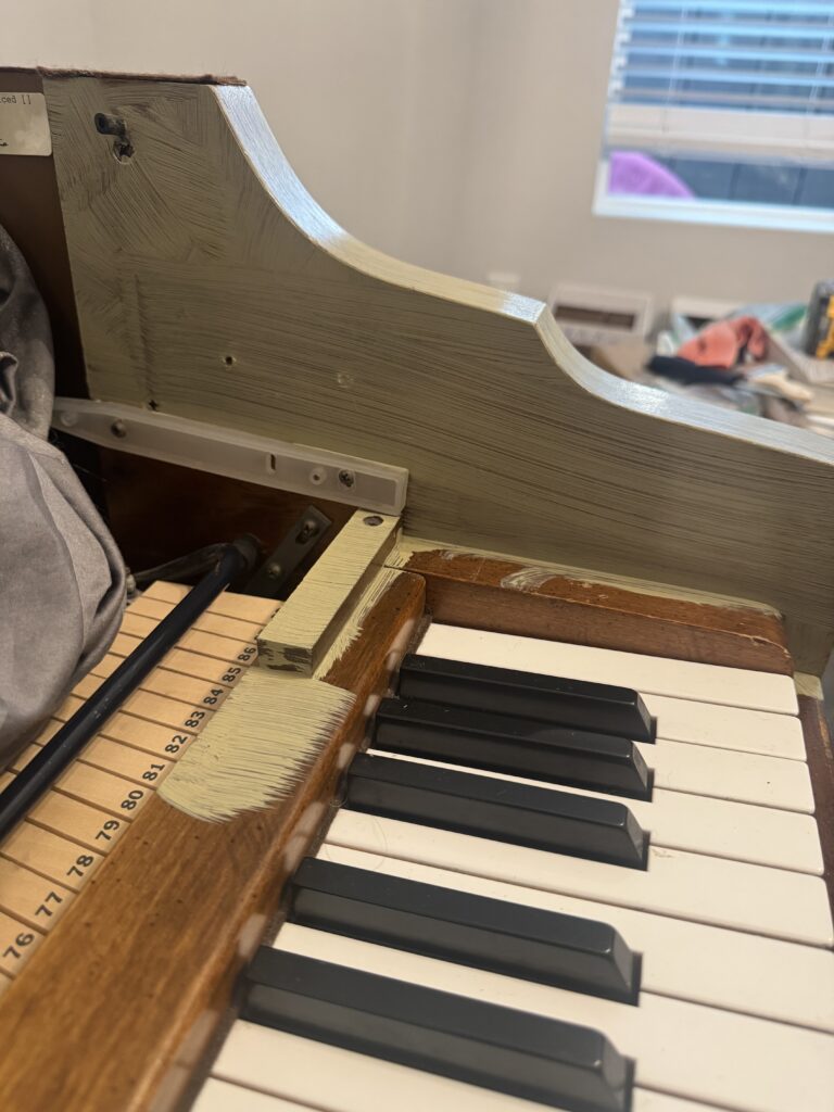 Close-up of piano keys and side panel during first coat of green paint.